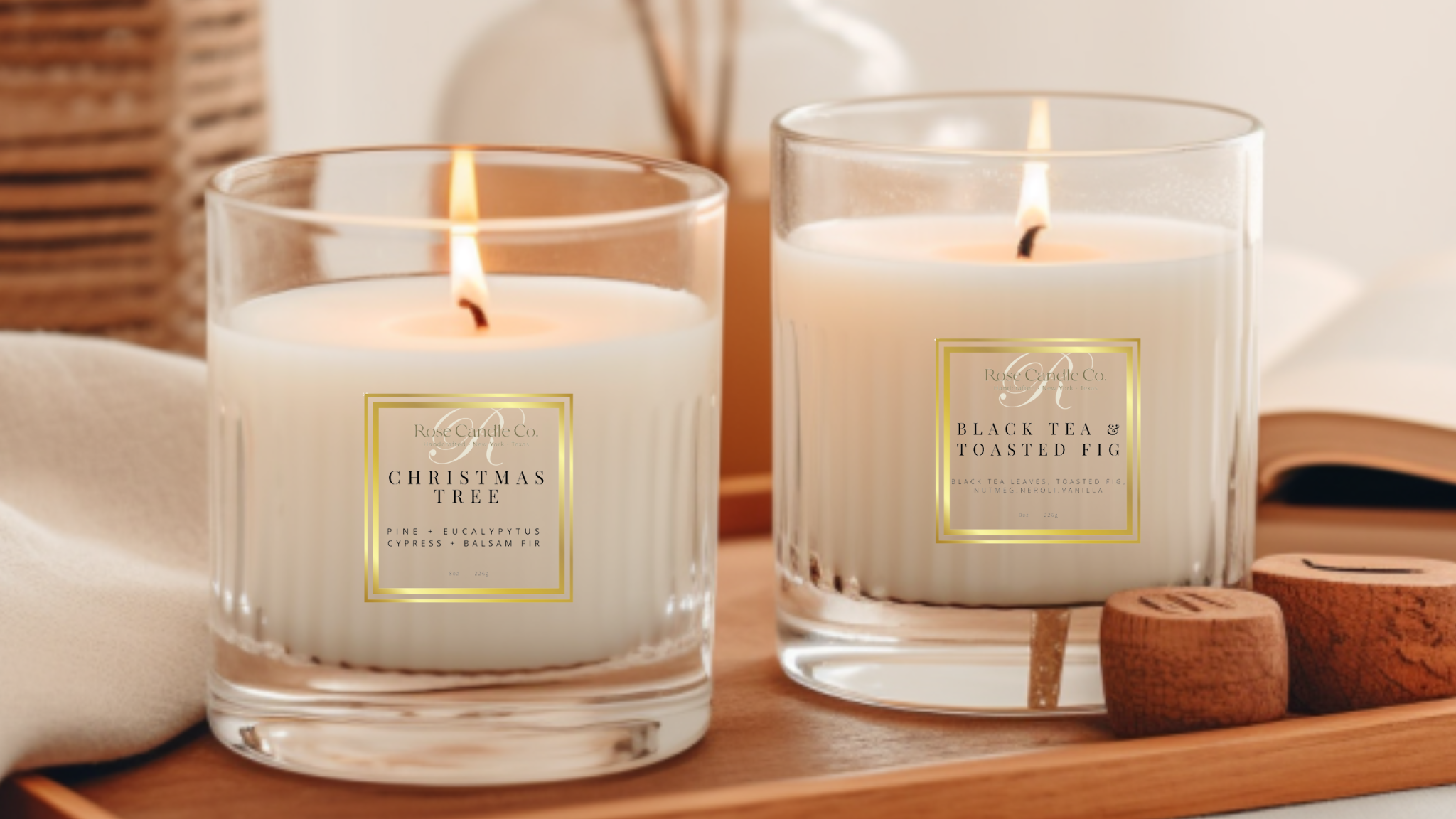 Two lit candles in glass jars with decorative labels on a wooden tray.