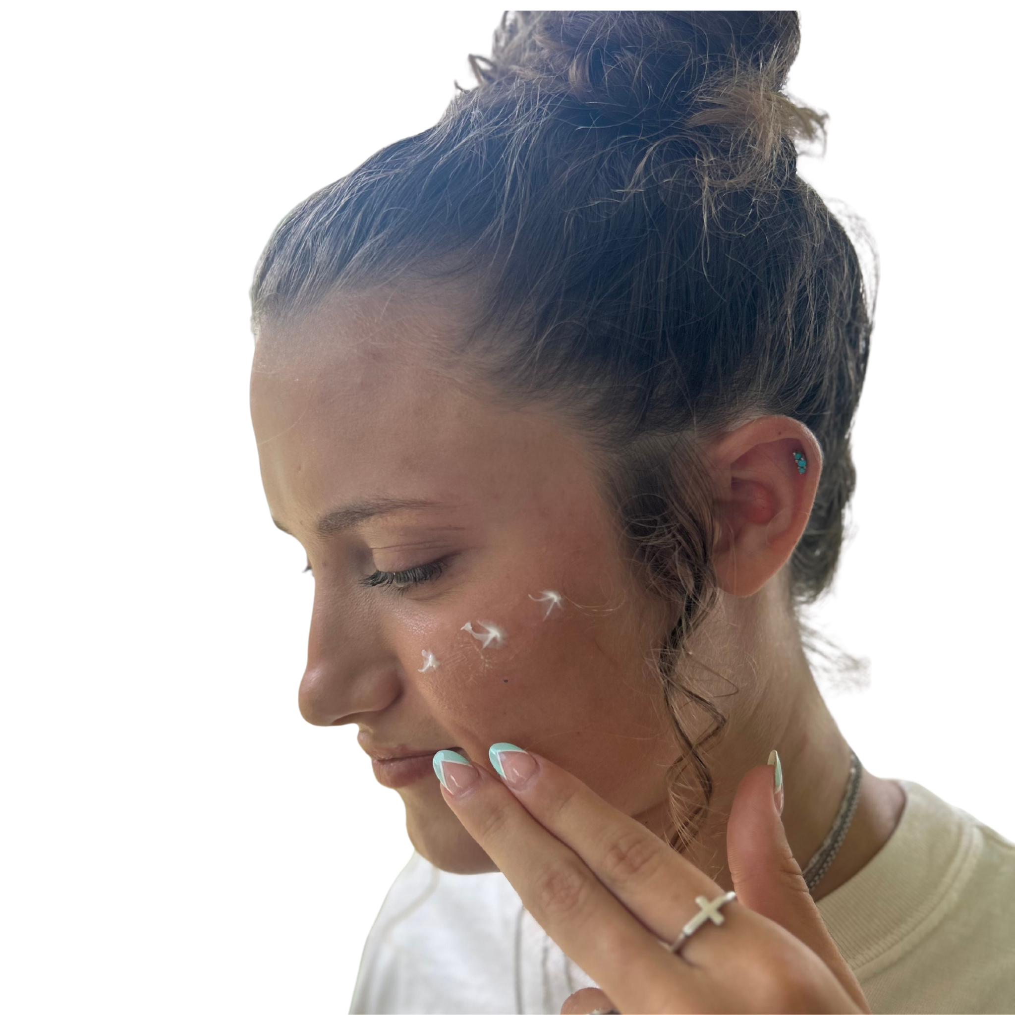 Woman applying cream to her face with a neutral background